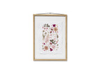 A framed botanical art featuring delicate pressed flowers and leaves in soft pink, burgundy, beige, and olive green tones. The print is mounted on a white textured sheet and enclosed in a light natural wood frame with a black hanging cord, shown against a solid white background.