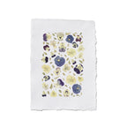 An unframed floral art print featuring pressed pansies in purple, blue, and yellow on a white textured paper on a white background.